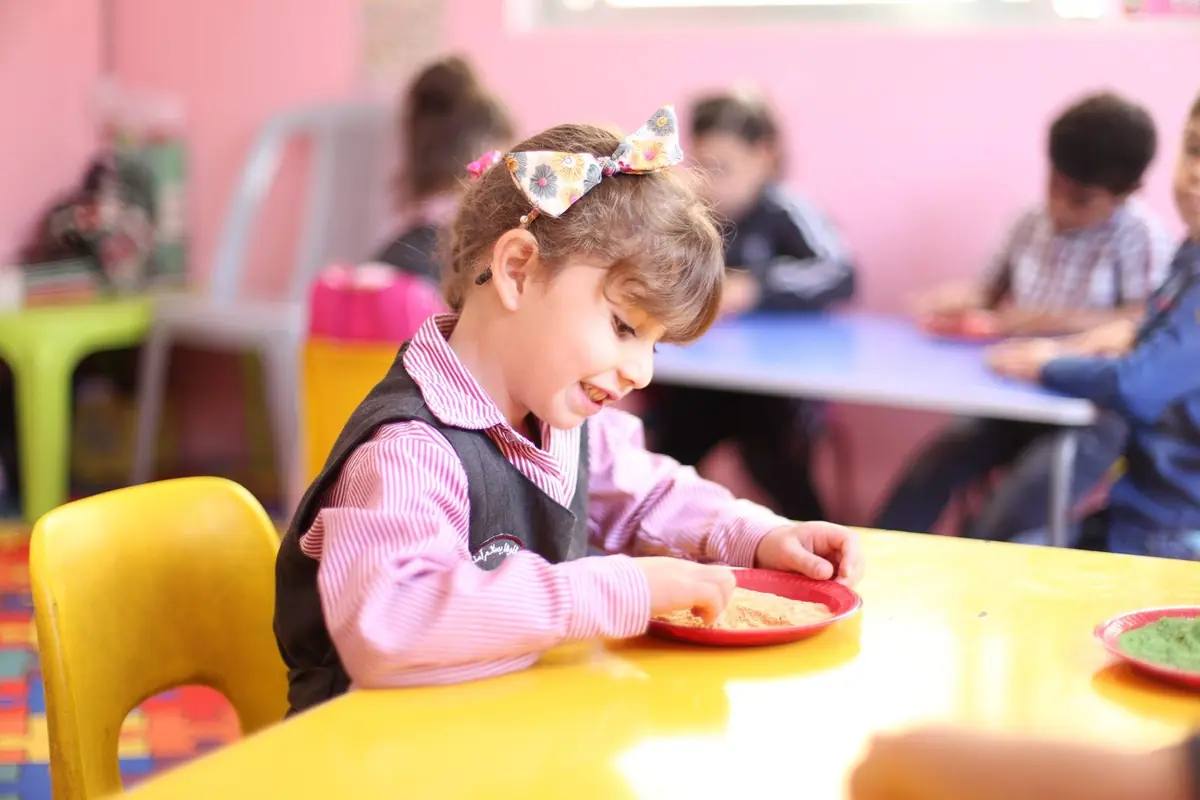 Niña de Inicial escribiendo con atención en su cuaderno