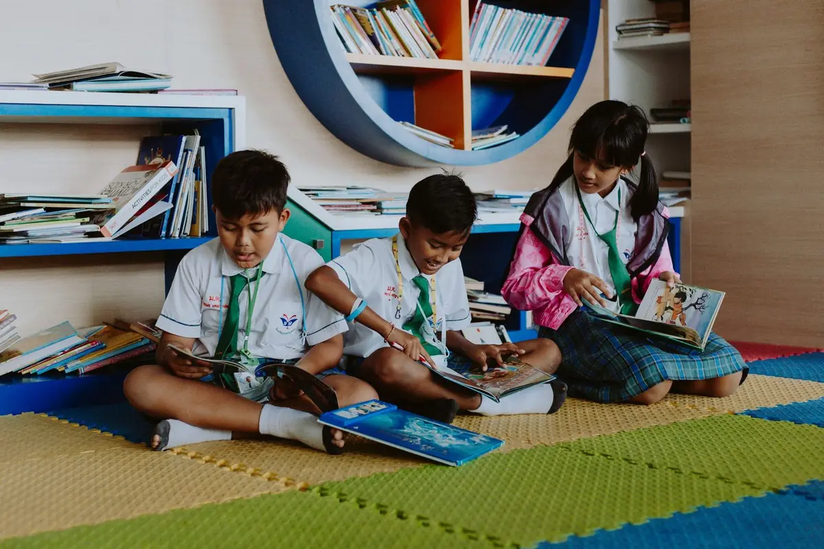 Niños leyendo en el suelo de la biblioteca escolar