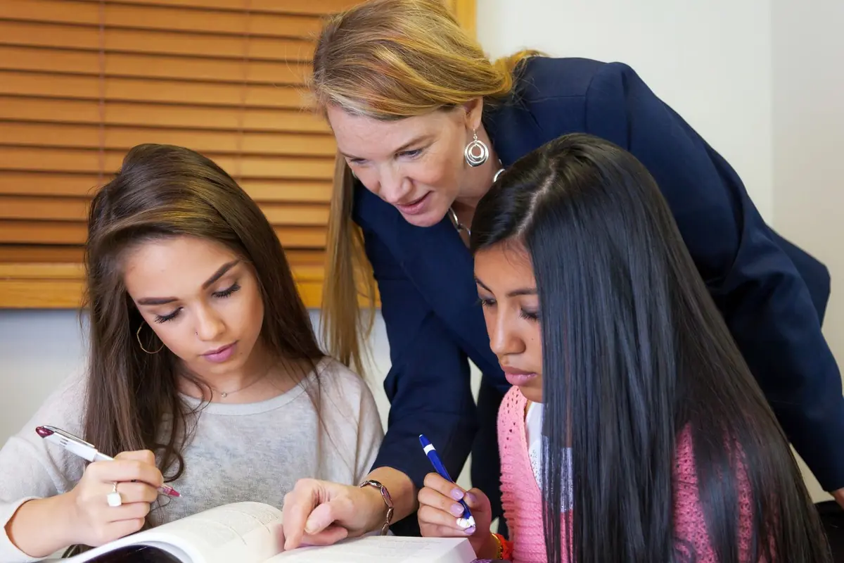 Profesora acompañando a dos estudiantes durante una actividad en clase